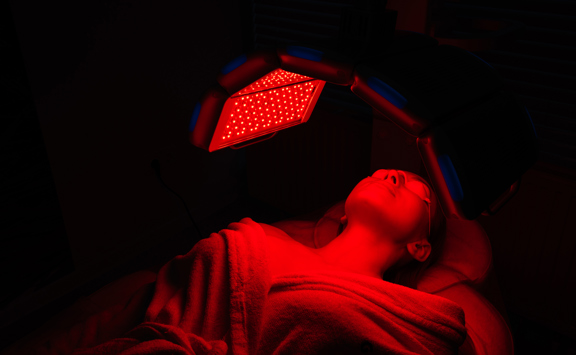 Side View Tracking Shot Relaxed Female Client Having Red Led Light Facial Photodynamic Therapy