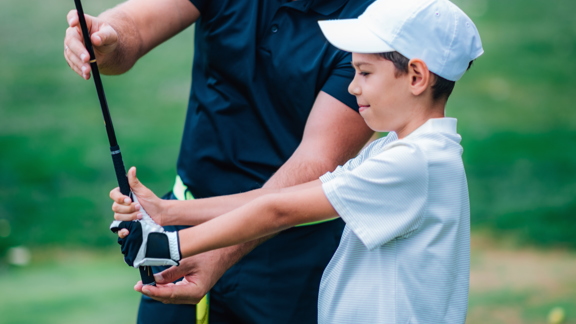 Golf Instructor Adjusting Young Boy S Grip